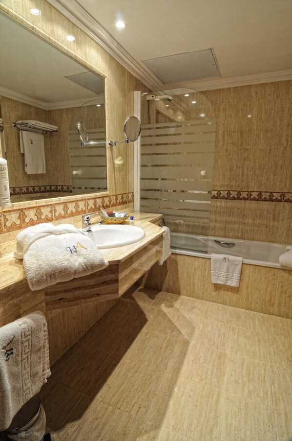 A bathroom with two sinks, a bathtub, and a large mirror.