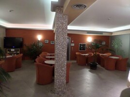 Un vestíbulo con asientos color naranja, un televisor y una columna decorativa.