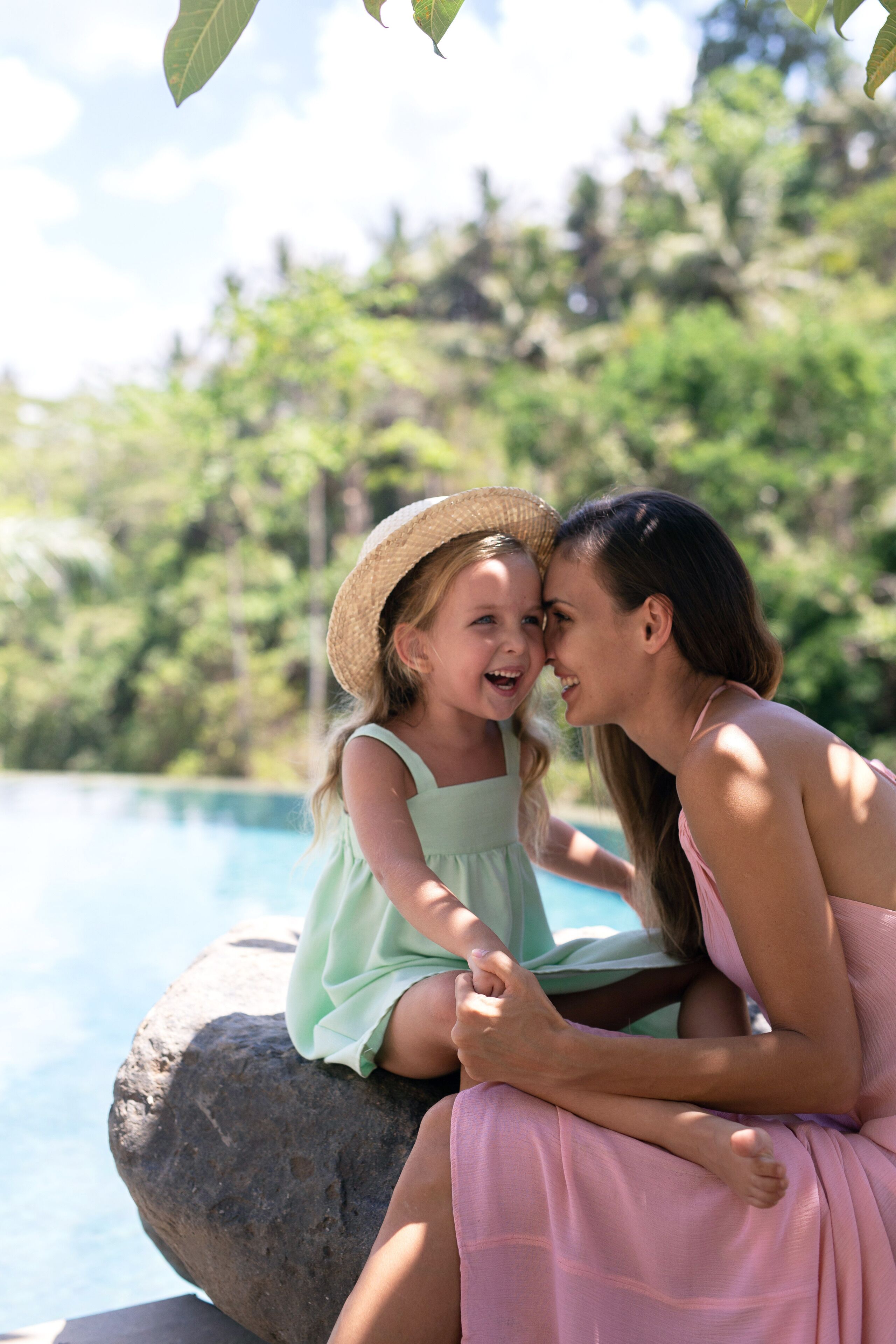 Two people sitting by a pool with a natural, green background.