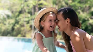 Two people sitting by a pool with a natural, green background.