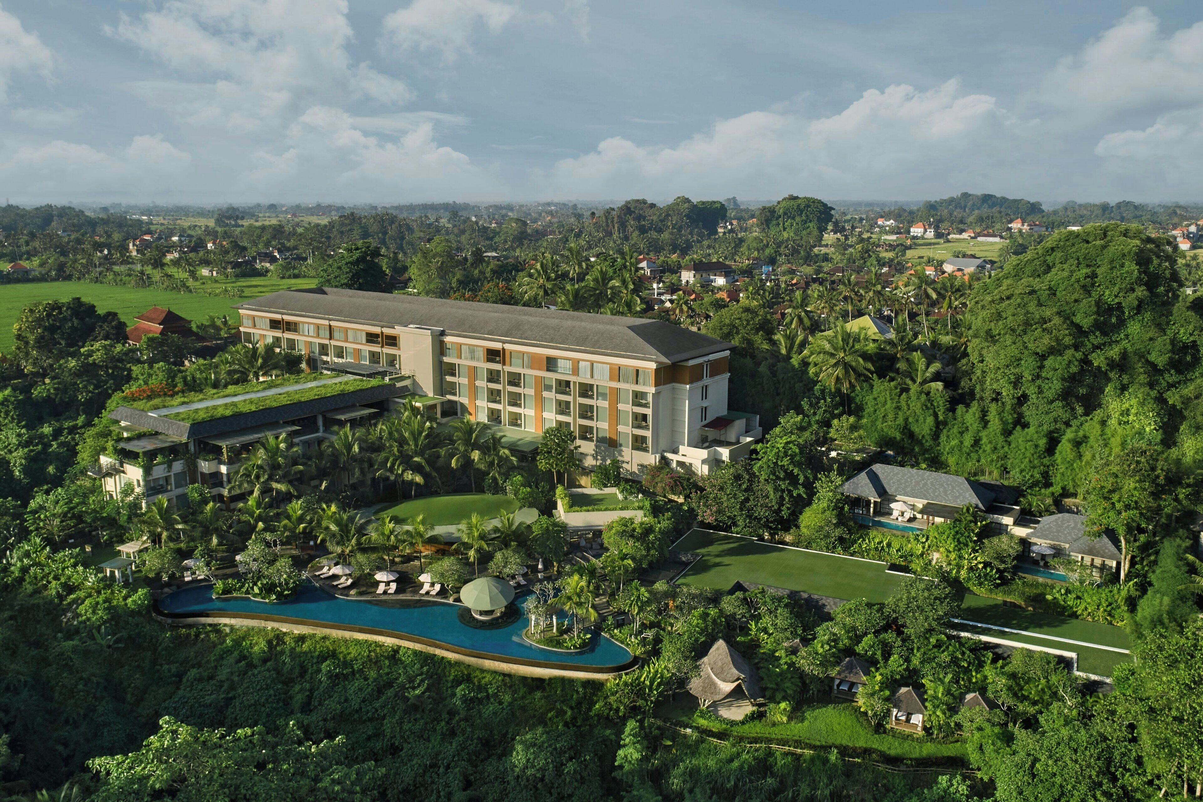 A large hotel with multiple buildings, a swimming pool, and lush greenery surrounding the property.