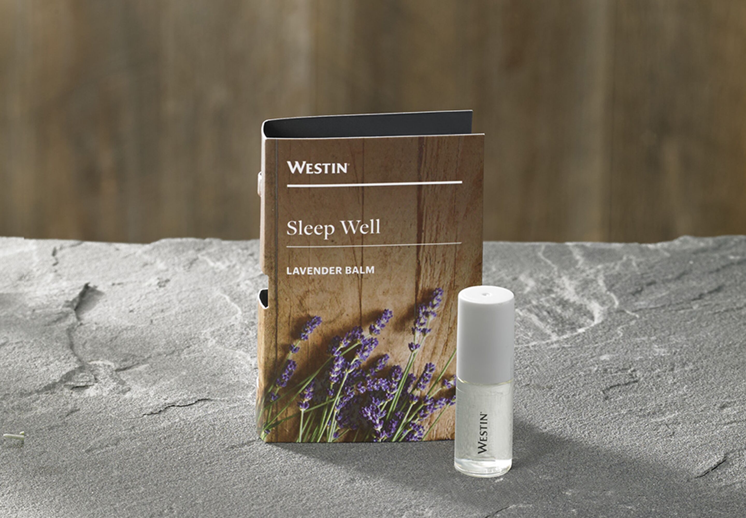 Un frasco y una caja de bálsamo relajante Westin Sleep Well sobre una superficie texturizada.