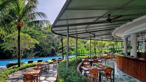 A covered outdoor seating area with tables and chairs, a pool, and lush greenery. - The Westin Resort & Spa Ubud, Bali (Ubud)