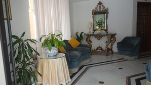 Un salon comprenant un canapé, deux fauteuils, une table basse et un miroir décoratif.