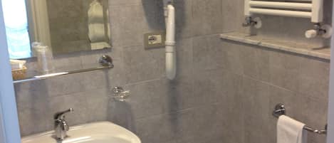 Un baño con lavamanos, bidé y perchero para toallas.