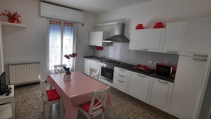 Une cuisine de taille réduite avec des meubles blancs, une table à carreaux rouges et blancs et un poêle.