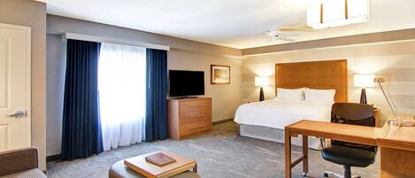 A hotel room with a bed, desk, chair, television, and a window with curtains.
