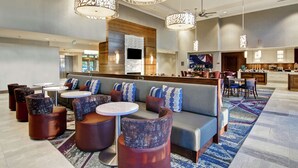 A modern hotel lobby with a seating area, a bar, and a kitchen visible in the background. - Homewood Suites by Hilton Ottawa Kanata (Ottawa)