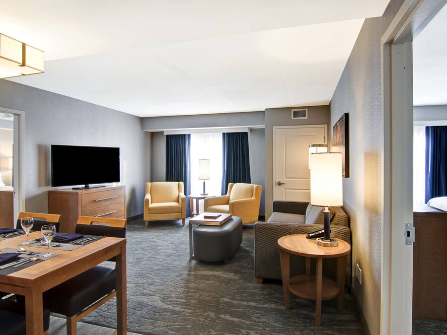 Een hotelkamer met een eettafel gedekt voor twee personen, een bank, een televisie en een bed.