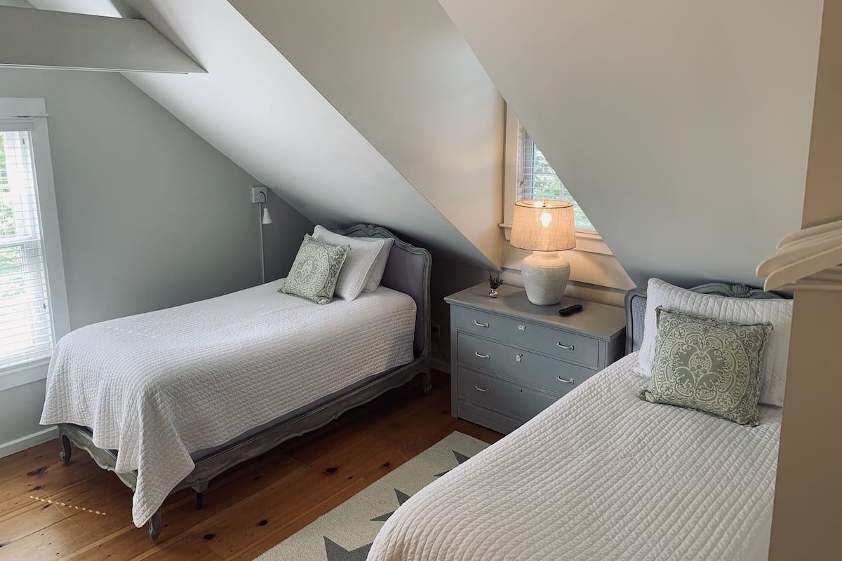 Ein Schlafzimmer mit zwei Betten, einem Nachttisch, einer Lampe und einem Fenster mit Blick.