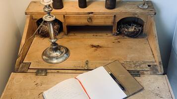 A rustic wooden desk with a lamp, a candle holder, and a decorative feather.