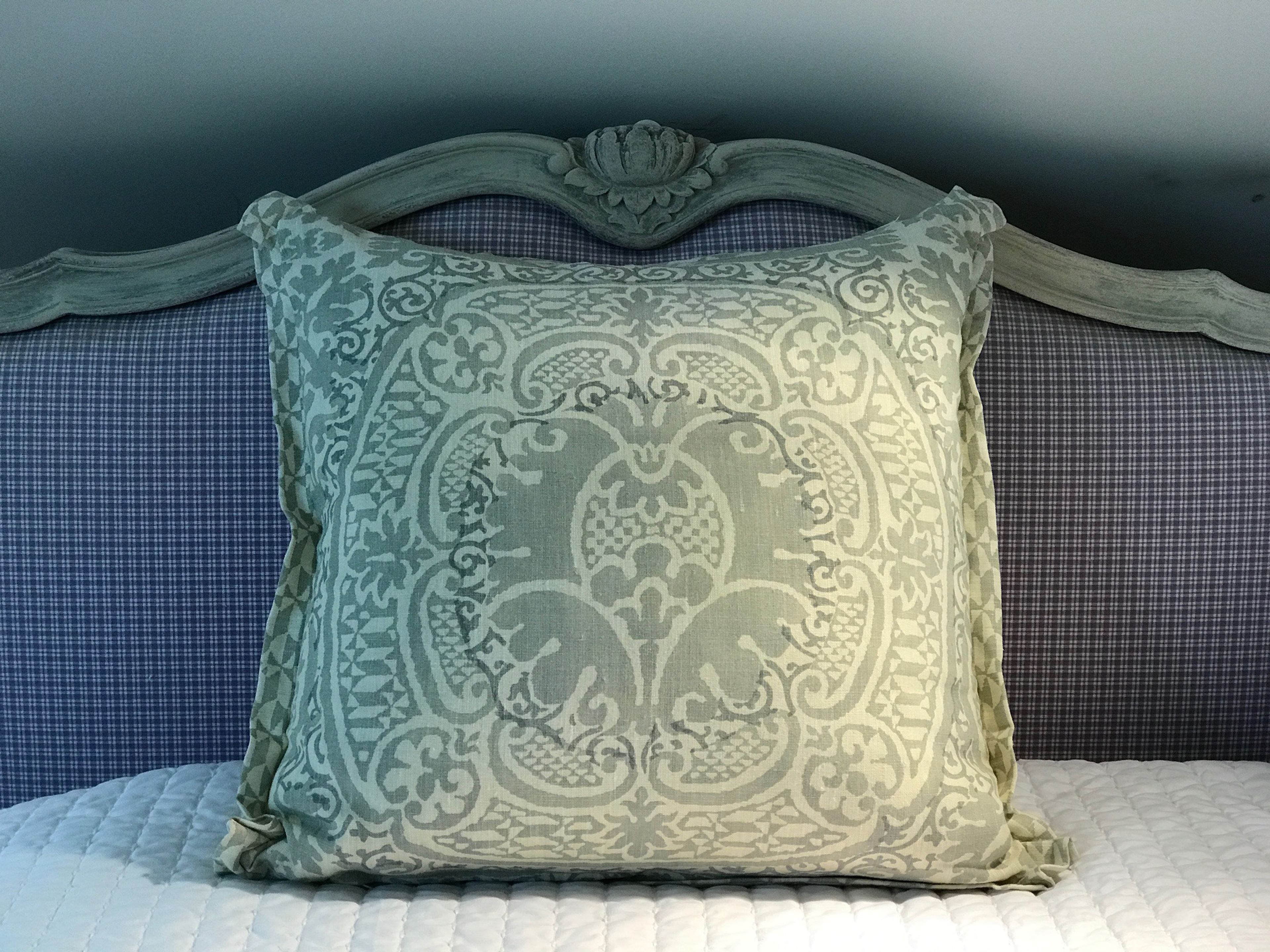 A bed with a patterned pillow and a headboard with a floral design.