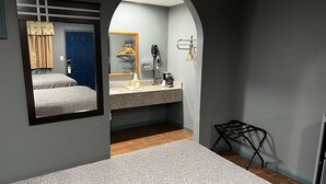 A hotel room with a bed, a bathroom with a mirror, a sink, and a small seating area.