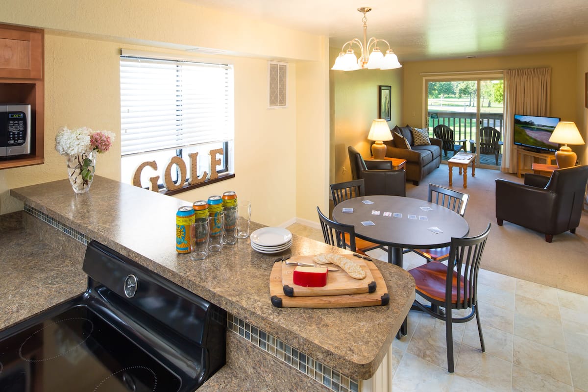 A kitchen with granite countertops, a built-in oven, and a dining area with a round table and chairs.
