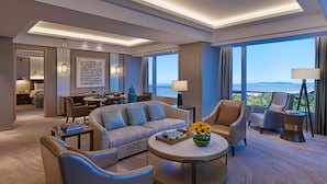 Een moderne hotelkamer met een bank, fauteuils, een zithoek en grote ramen met uitzicht op de oceaan.