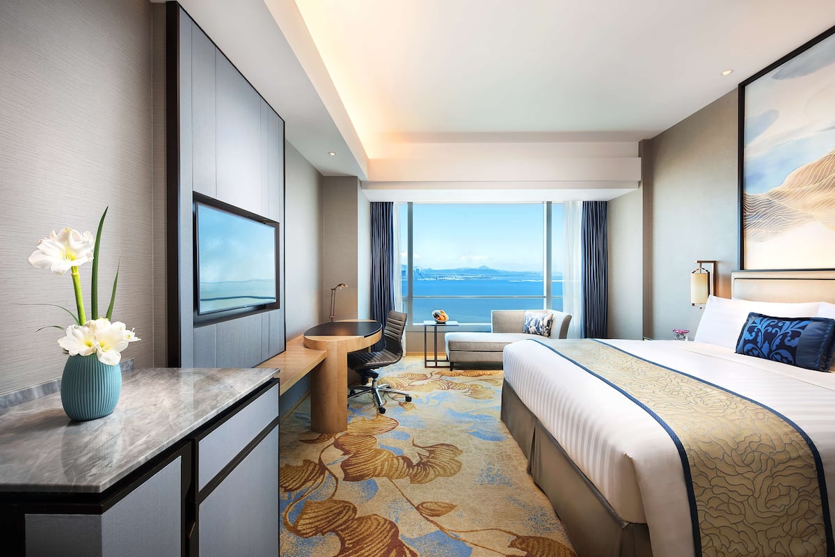 Une chambre d’hôtel équipée d’un lit, d’un bureau, d’une chaise et offrant une vue sur le paysage urbain.