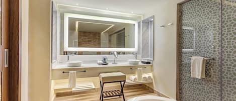 A modern bathroom with a large mirror, two sinks, a bathtub, and a glass shower enclosure.