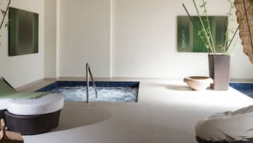A spa room with a hot tub, seating area, and potted plants.