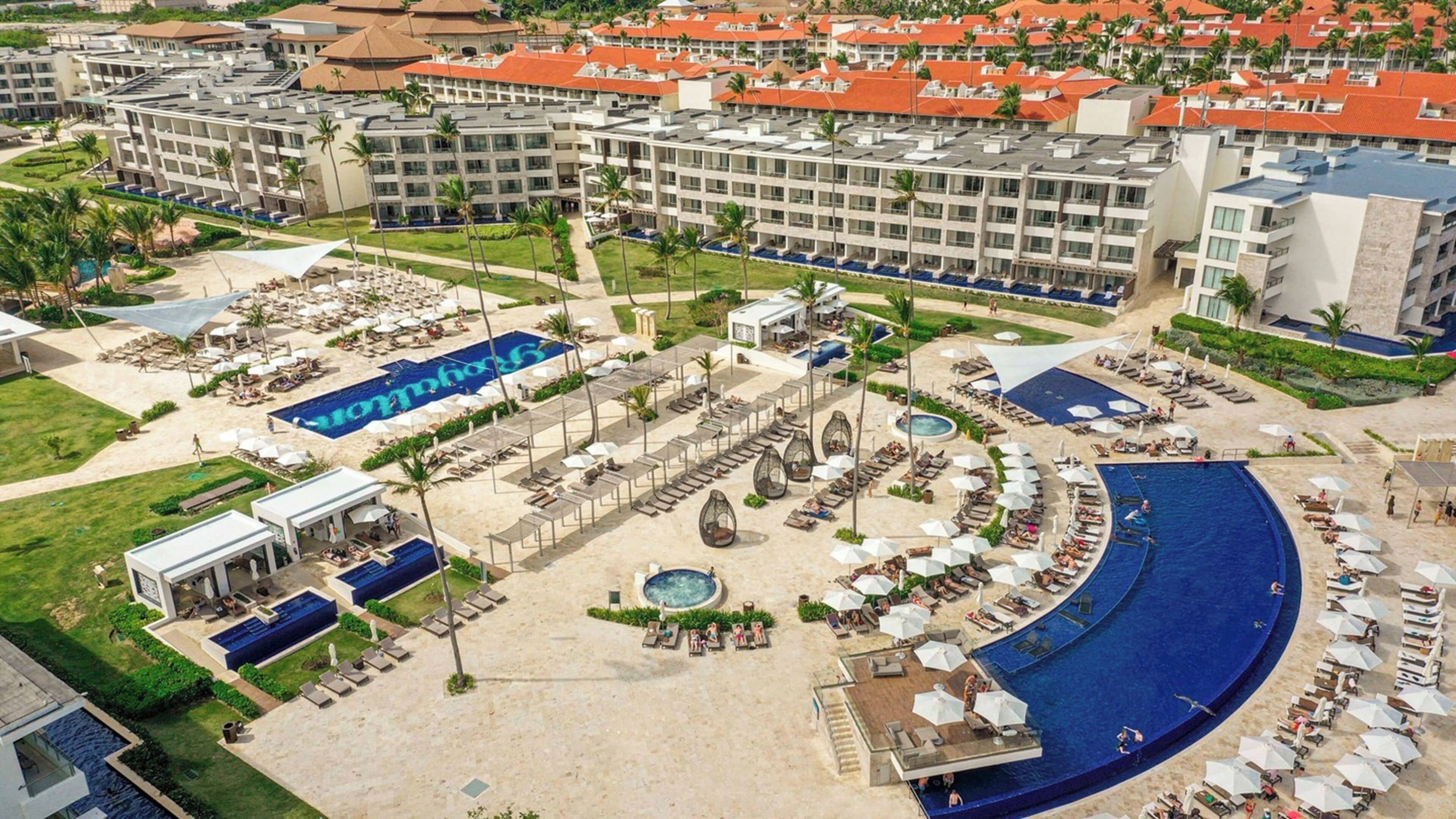 Un complexe hôtelier doté de plusieurs piscines, de chaises longues et d’un élément aquatique central.