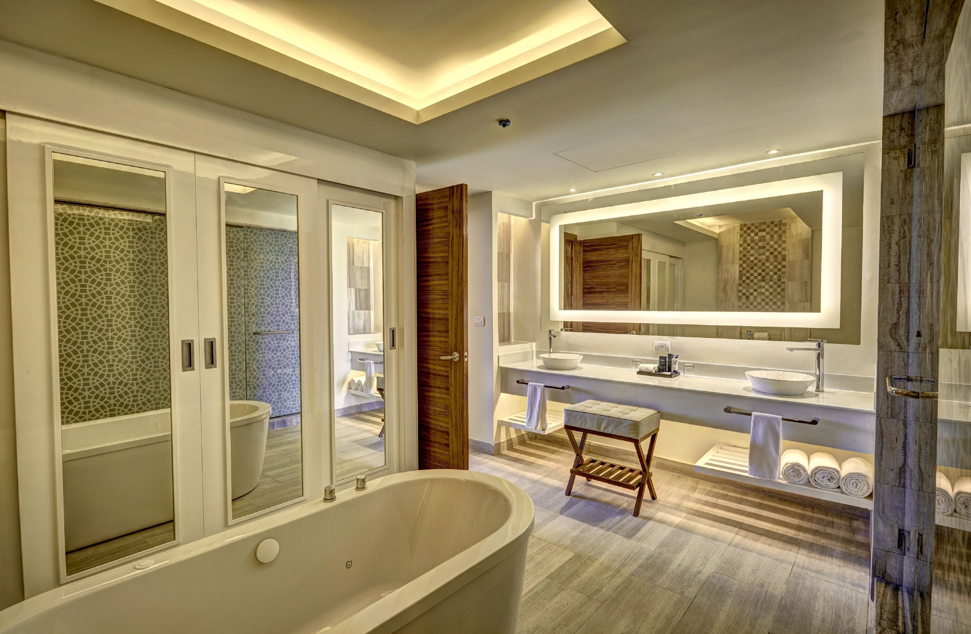 A modern bathroom with a freestanding bathtub, a large mirror, and a vanity with a sink and towel rack.