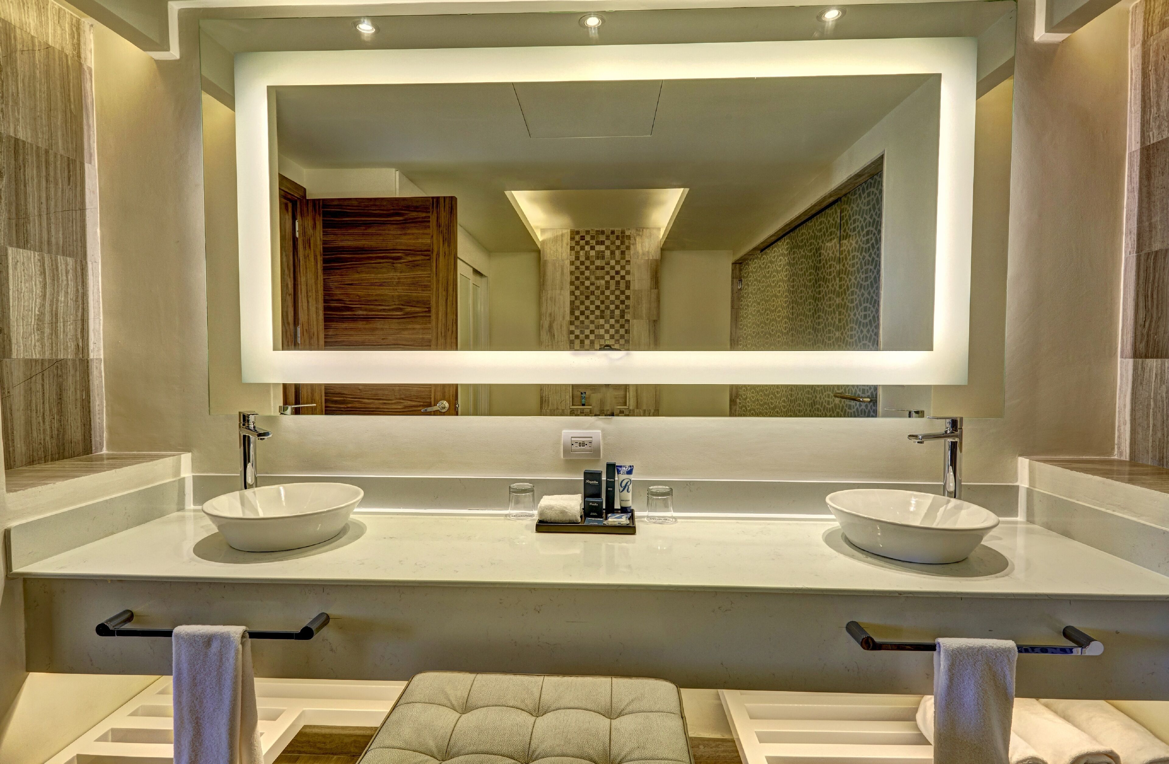 A modern bathroom with a large mirror, two sinks, and a towel rack.