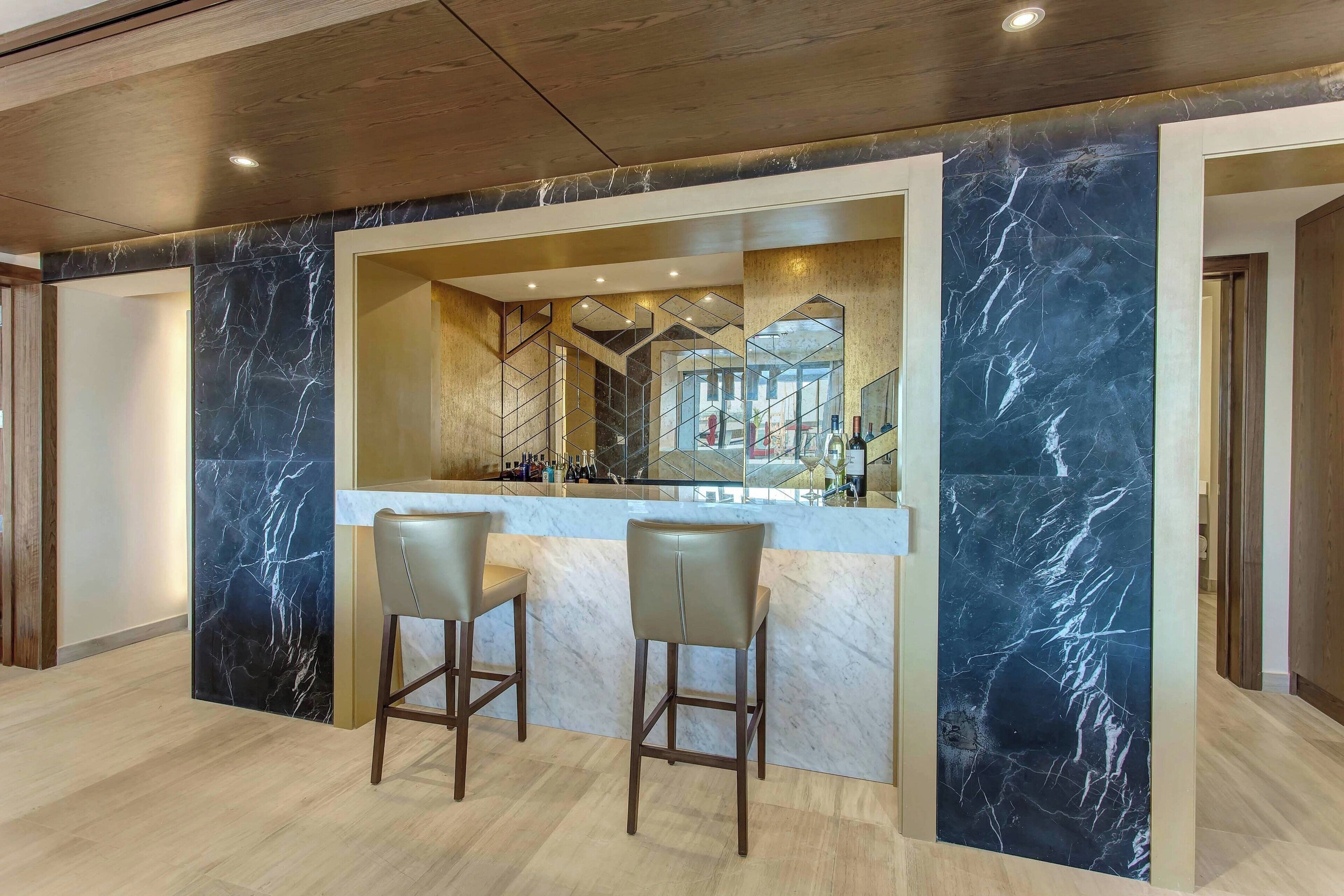 A bar area with marble walls and two bar stools.