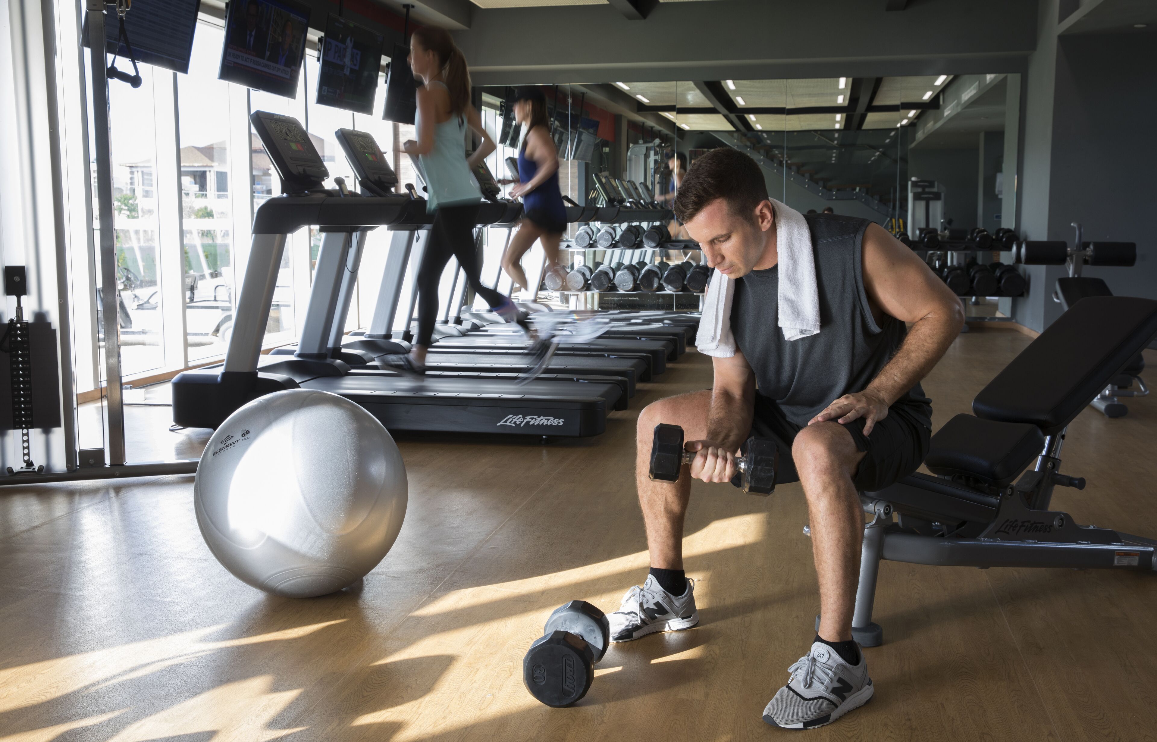 Een sportschool met loopbanden, gewichten en fitnessballen.
