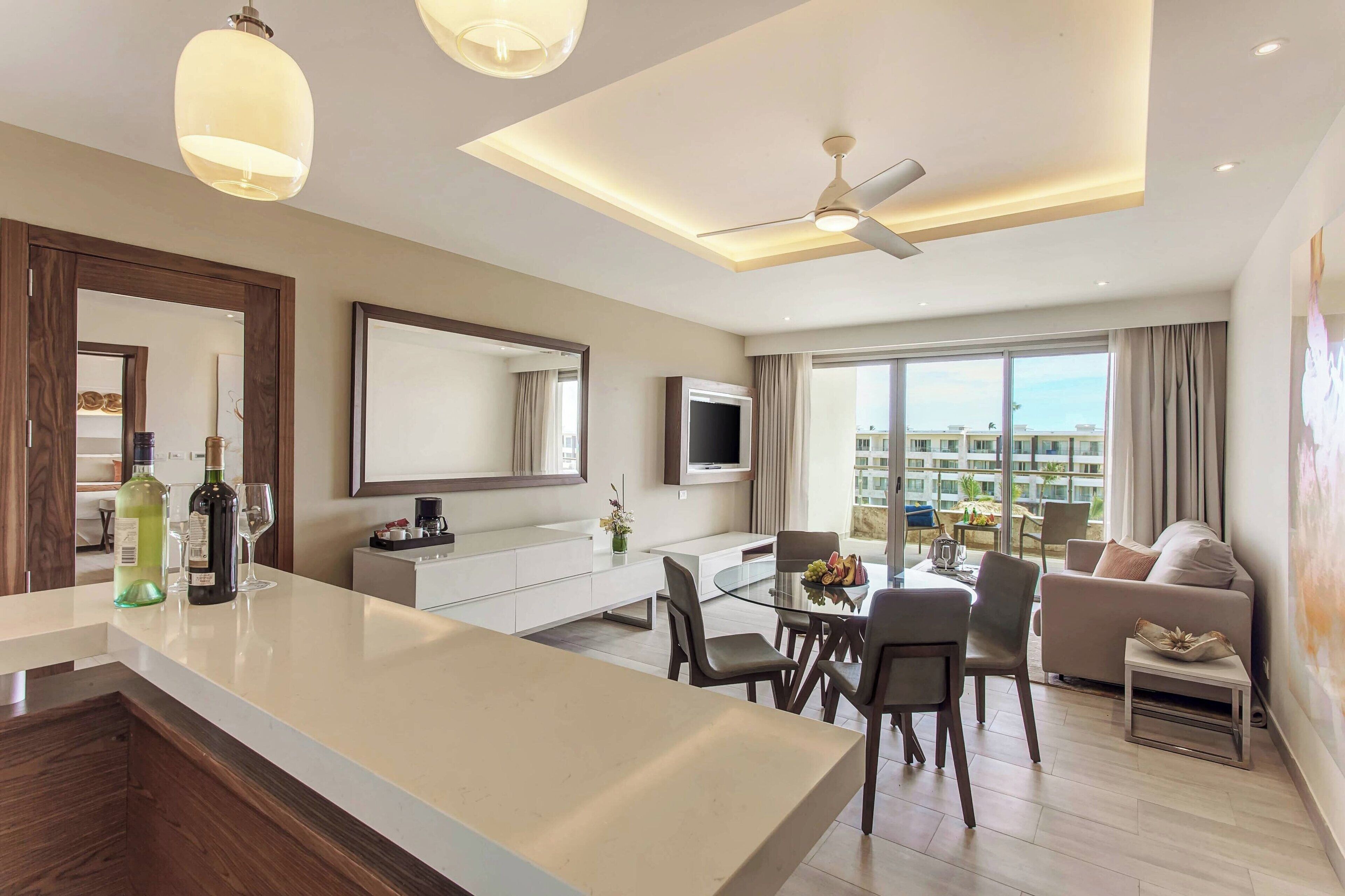A modern hotel room with a central island, dining area, and a living space.