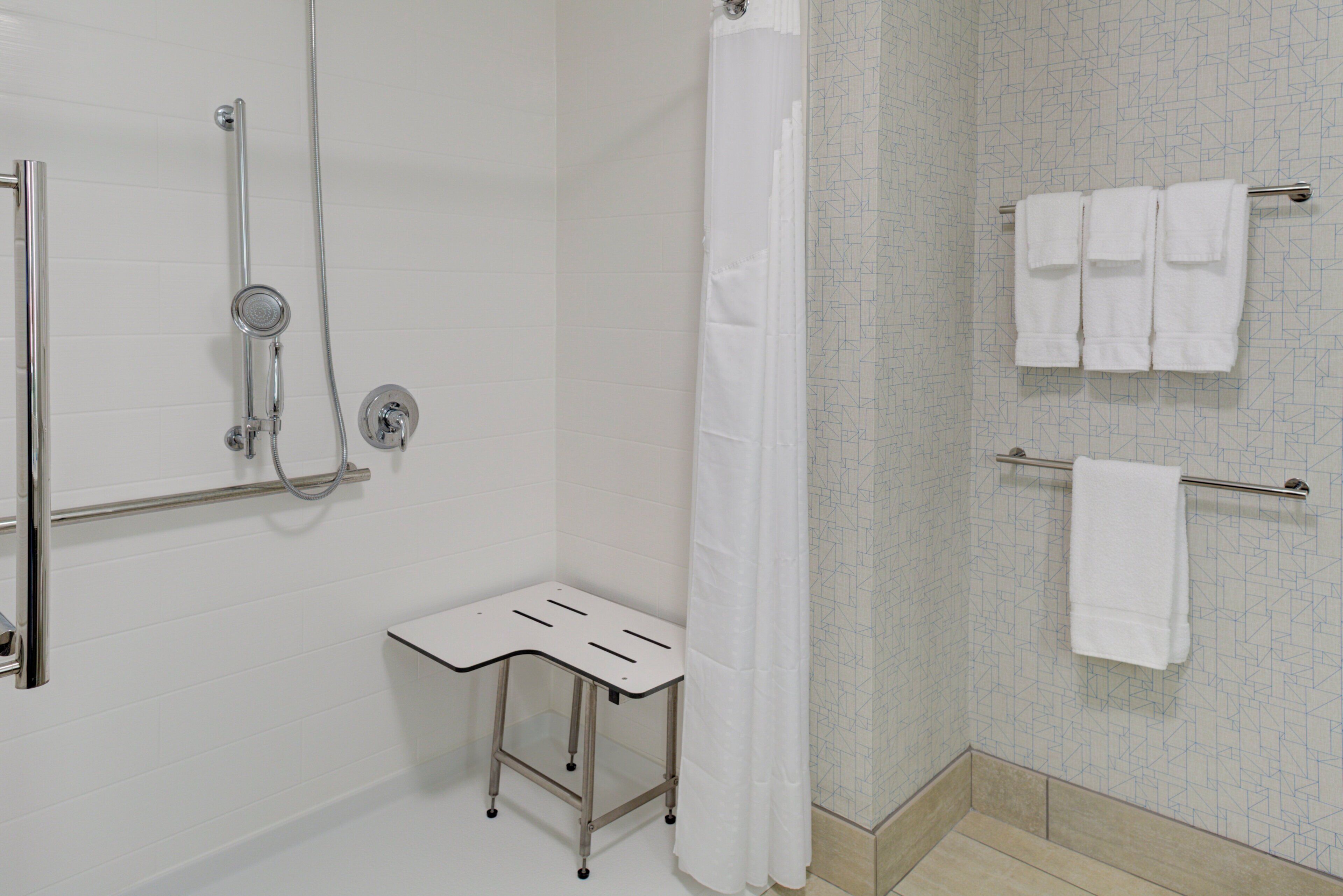 A bathroom with a shower, a towel rack, and a small table.