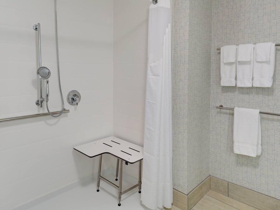 Ein Badezimmer mit Dusche, Handtuchhalter und einem kleinen Tisch.