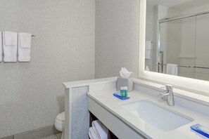 Casa de banho moderna com lavatório branco, espelho e porta-toalhas.