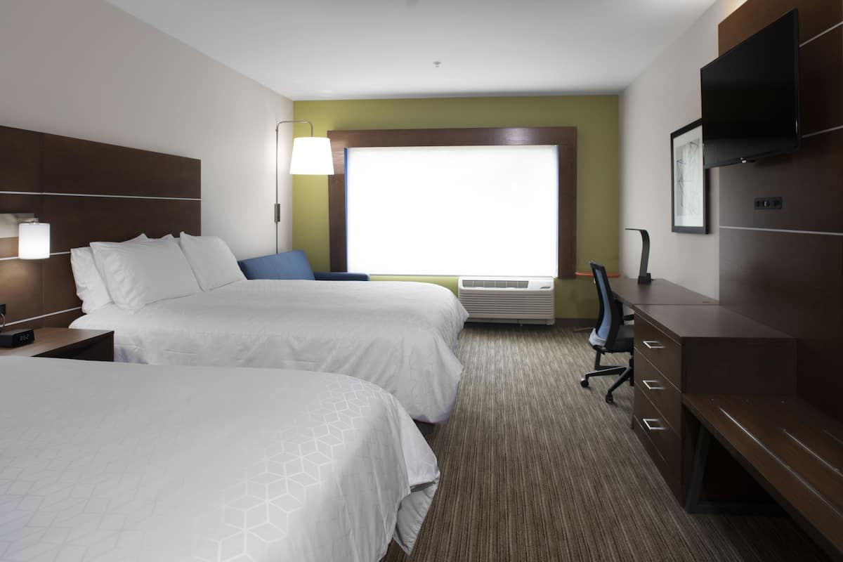A hotel room with two beds, a desk, a chair, a flat-screen TV, and a window with a view.