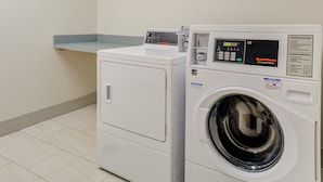 A front-loading washing machine and a dryer in a laundry room with a tiled floor. - Holiday Inn Express and Suites King George- Dahlgren by IHG (King George)