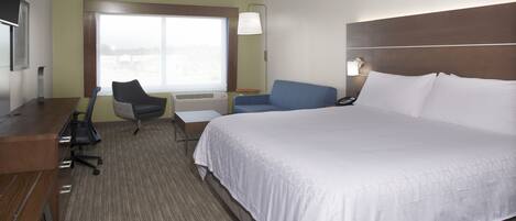 A hotel room with a large bed, a desk, a chair, and a window with a view.