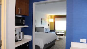 A hotel room with a bed, a desk, a chair, a microwave, and a coffee maker.