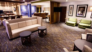 A hotel lobby with a sofa, chairs, a small table, a bar area, and a television. - Holiday Inn Express and Suites Gettysburg by IHG (Gettysburg)