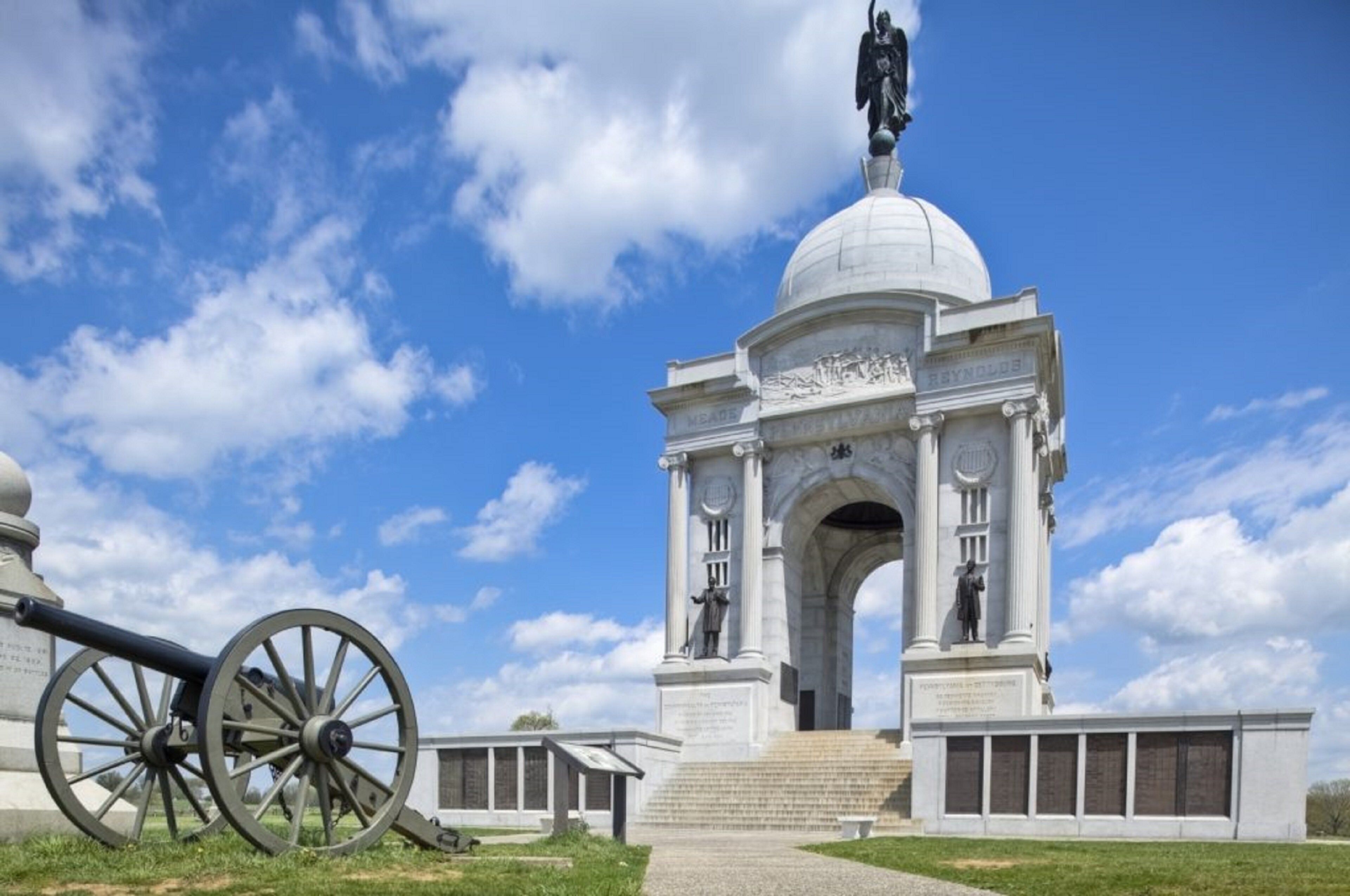 Un monument historique doté d’un dôme et de statues, ainsi qu’un canon, le tout sous un ciel d’un bleu éclatant.