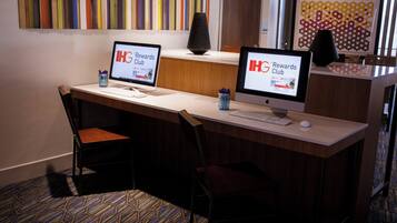 Mostrador de recepción de hotel con dos monitores mostrando el logo de 'IHG Rewards Club', un teclado, un ratón y una silla.