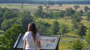 A person standing at an informational display with a view of a green landscape in the background. - Holiday Inn Express and Suites Gettysburg by IHG (Gettysburg)