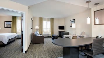 A hotel room with a bed, a desk, a chair, a TV, and a window with curtains.