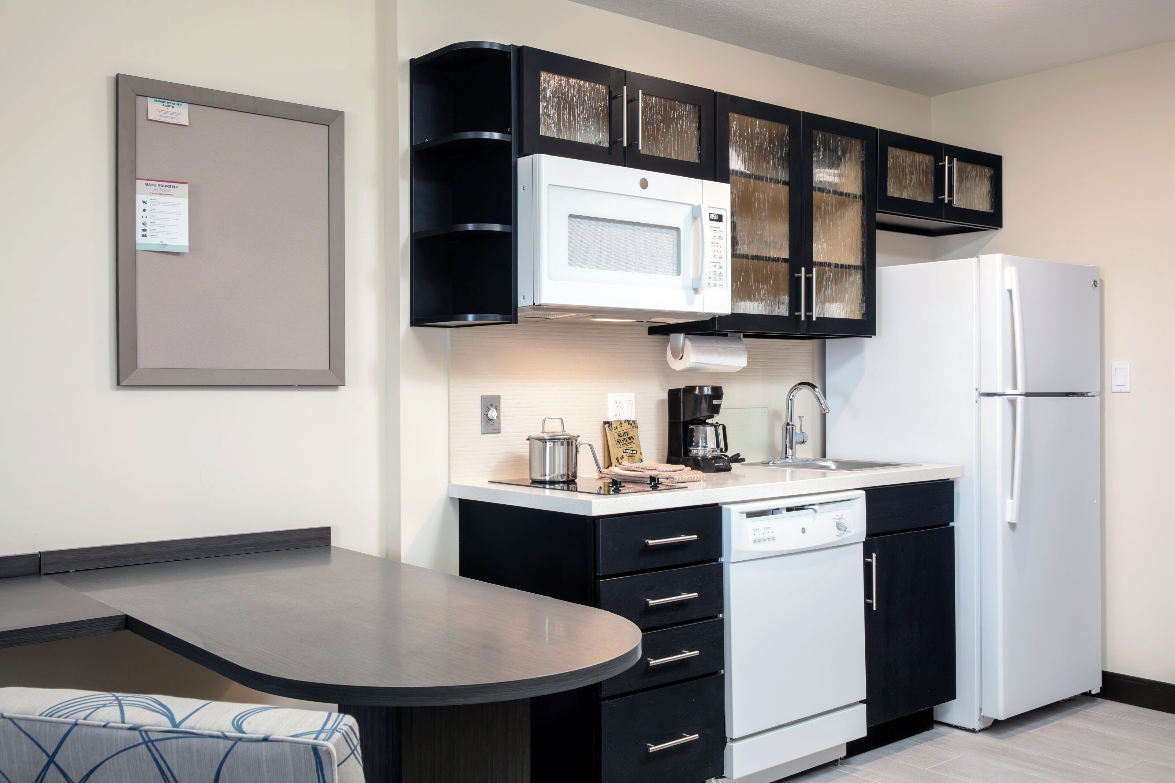 A compact kitchen with a microwave, coffee maker, and a refrigerator.