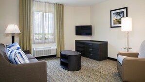 A hotel room with a sofa, a round table, a TV, a cabinet, and a window with curtains.