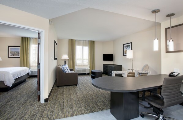 Une chambre d’hôtel comprenant un lit, un canapé, une table à manger, un téléviseur et un bureau.