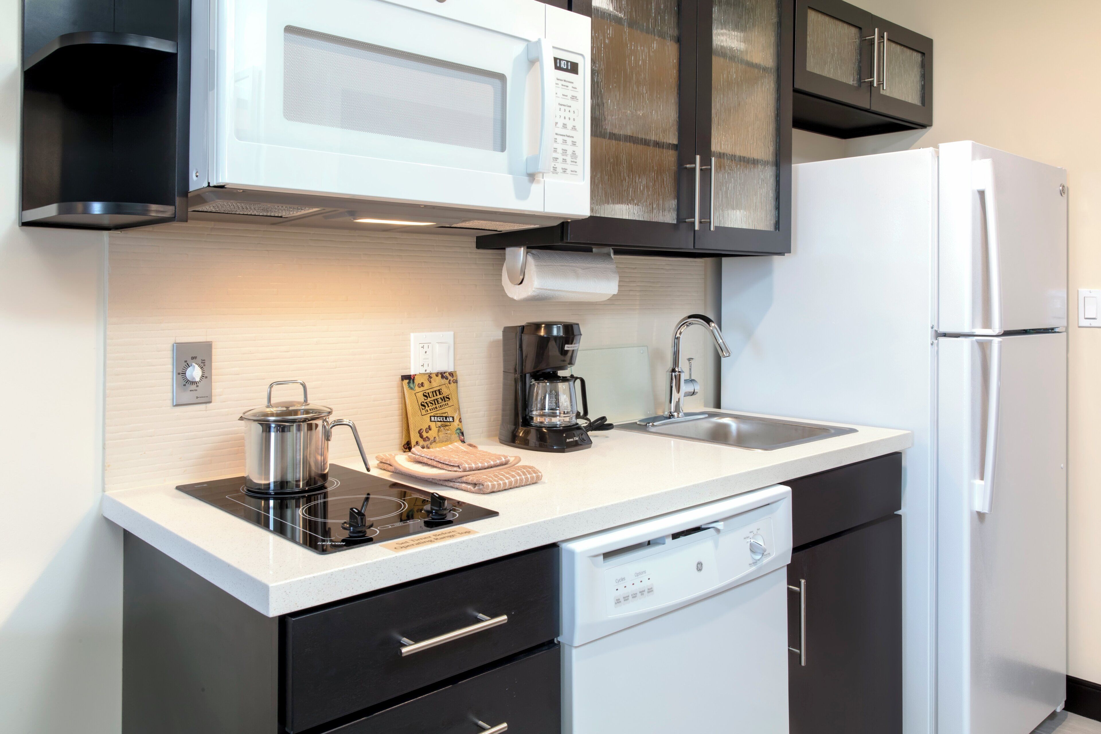 A modern kitchen with a built-in microwave, coffee maker, and dishwasher.