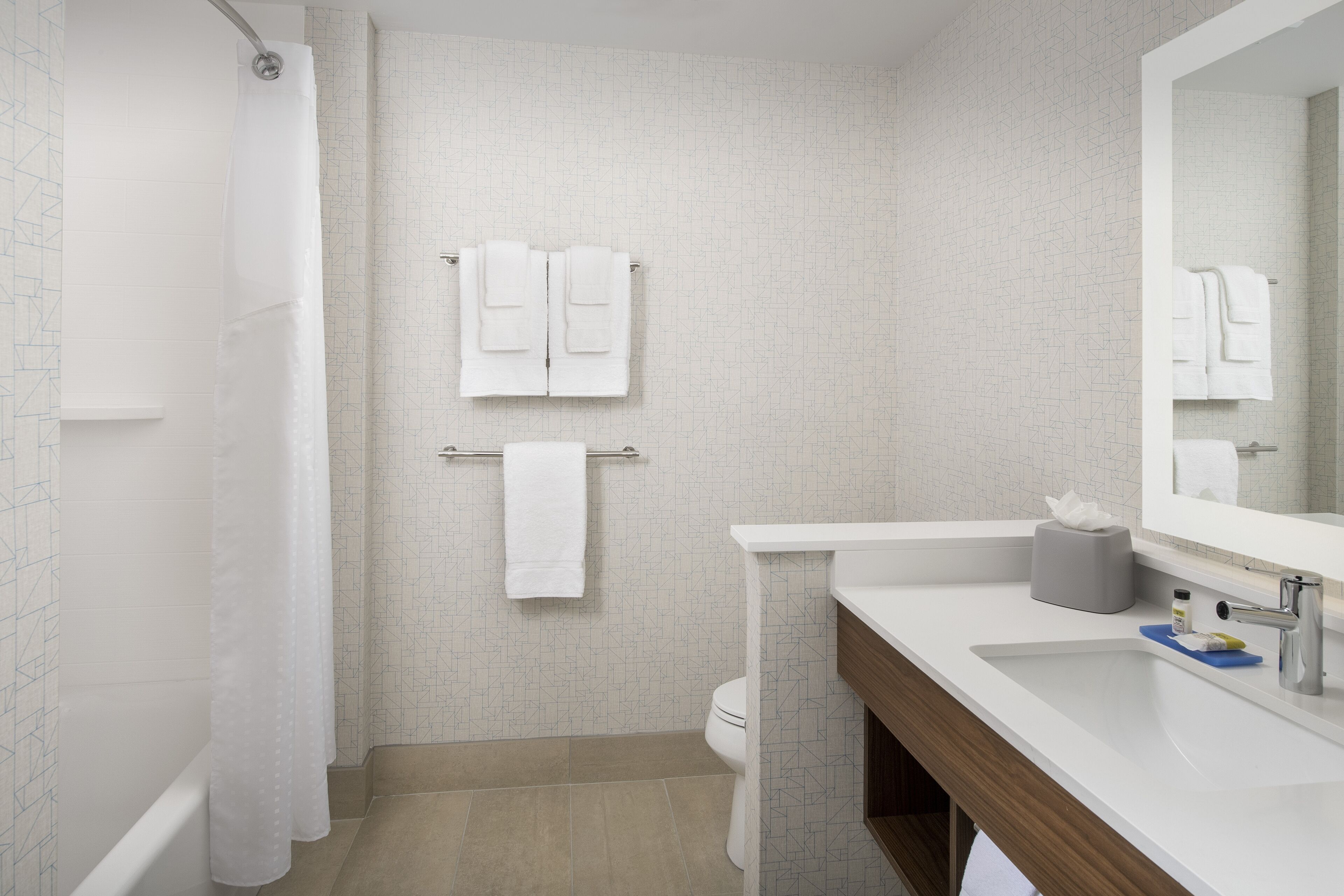 A modern bathroom with a shower, toilet, and sink.