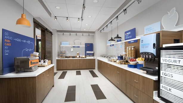 A modern kitchen with a central island, wooden cabinets, and a refrigerator displaying yogurt, eggs, and milk. - Holiday Inn Express and Suites North Brunswick by IHG (North Brunswick)