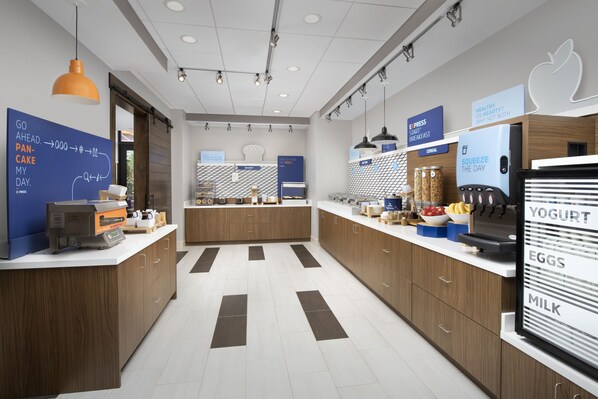 A modern kitchen with a central island, wooden cabinets, and a refrigerator displaying yogurt, eggs, and milk. - Holiday Inn Express and Suites North Brunswick by IHG (North Brunswick)