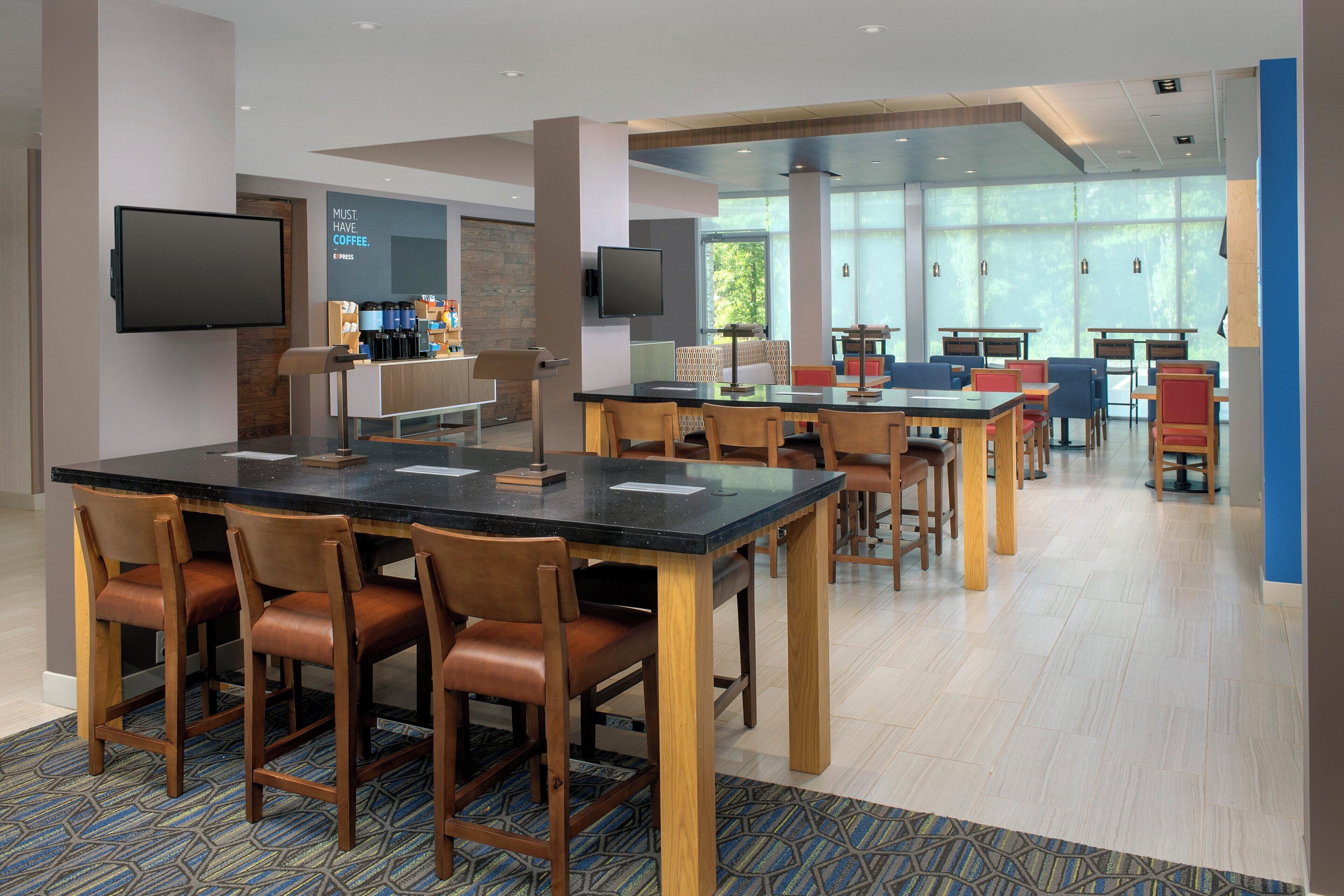 A modern dining area with a long table, chairs, and a coffee station.