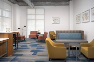 Un área de descanso moderna con un sofá, sillones, una mesita y un escritorio.