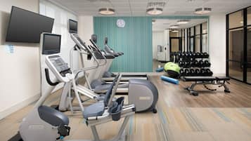A gym with treadmills, an elliptical, a bench, and a rack of dumbbells.